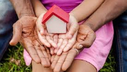 adult and child hands holding tiny house