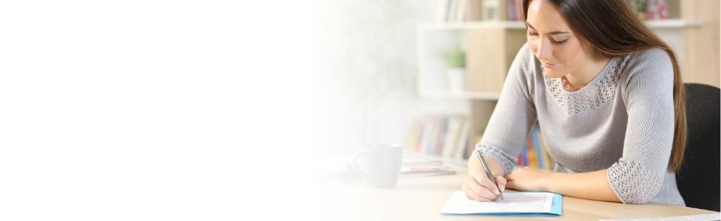 Woman sitting at desk filling out a paper survey with a pen