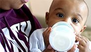 infant drinking out of baby bottle