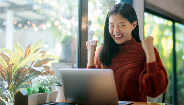 Mujer celebrando mientras usa una computadora portátil Mujer celebrando mientras usa una computadora portátil