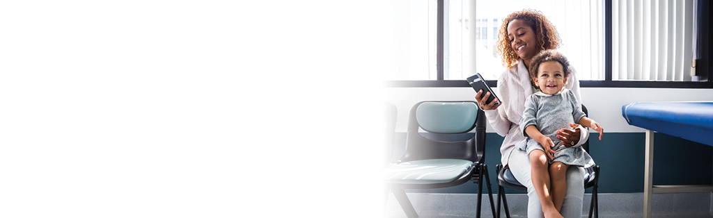 woman holding child and looking at cell phone